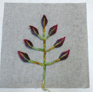 Image of floral stem and leaf crochet motif applique arranged symmetrically on stabilized pillow cover panel